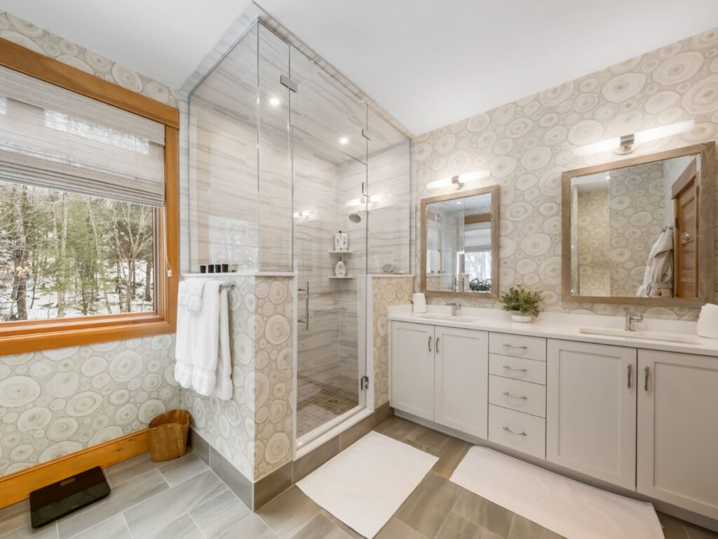 A modern bathroom with a glass shower, double sinks, and wood accents.