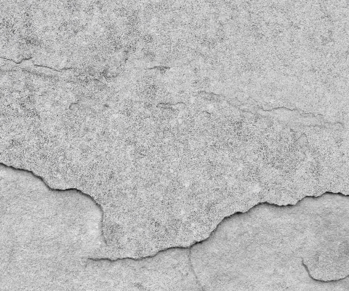 Diagonal crack running across rough concrete wall surface.