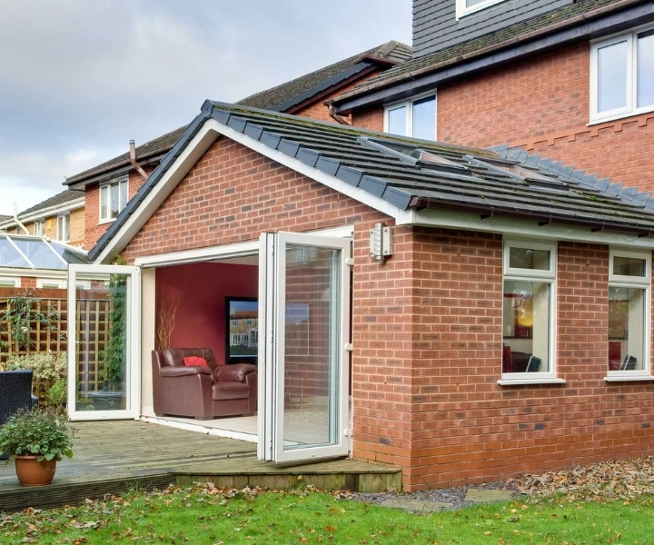 Brick house extension with open glass doors leading to garden.
