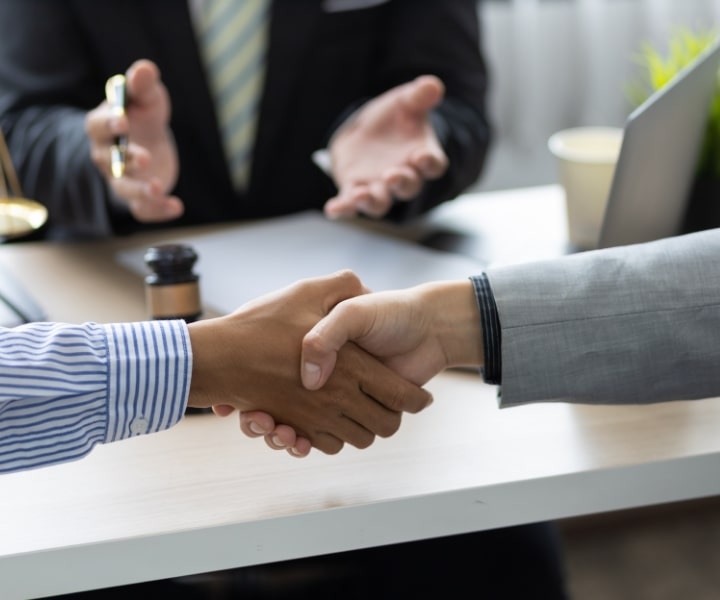 Two people shaking hands in legal office setting