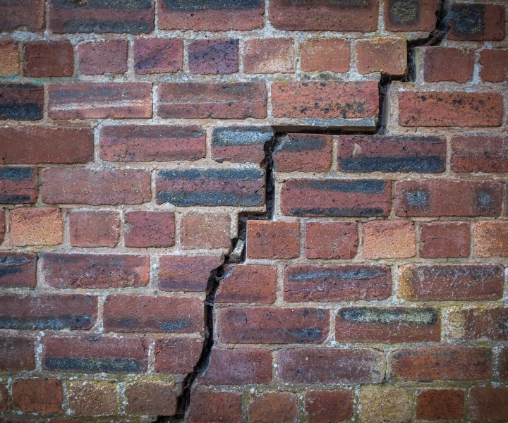 Stair-step crack running through red brick wall mortar joints.