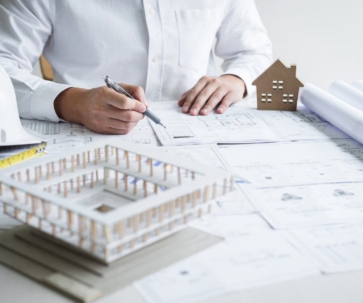 Architect reviewing building plans with model and construction documents.