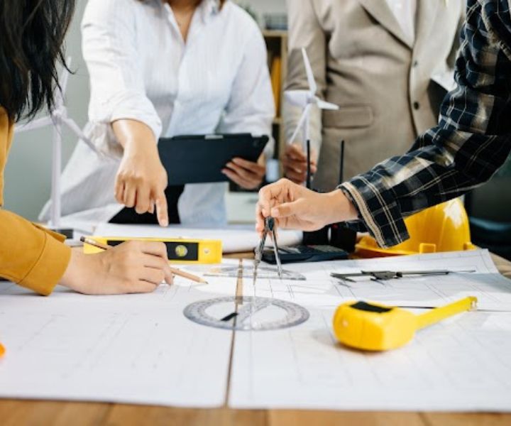 Engineers collaborating on blueprints with measuring tools and construction equipment.
