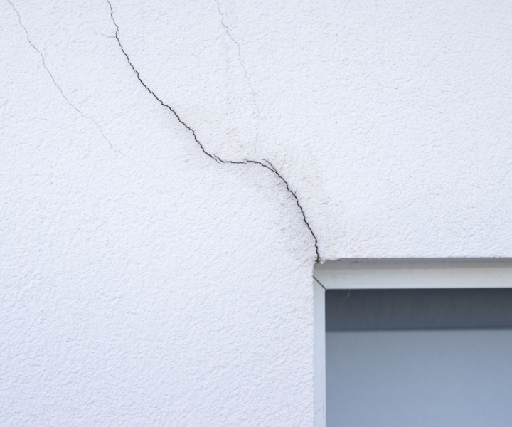 Diagonal crack forming above window on exterior wall.