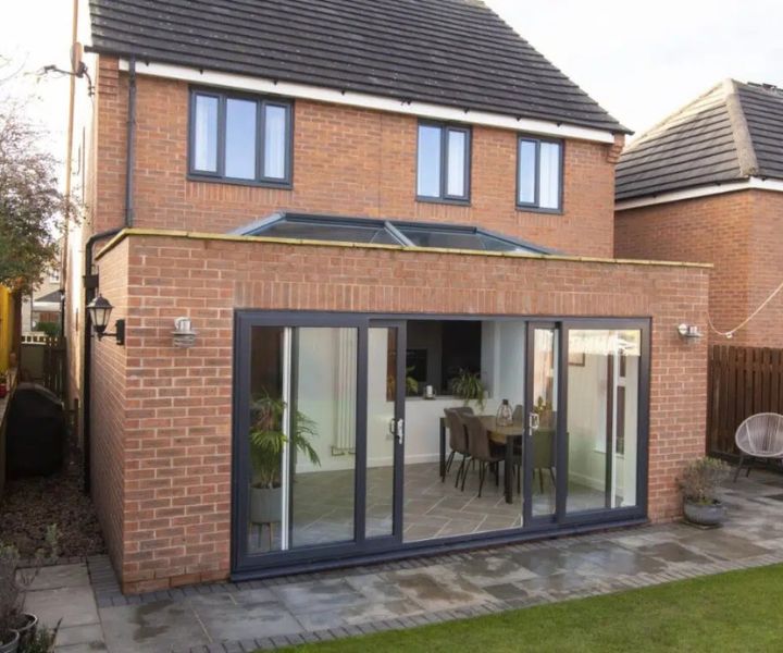 Contemporary single-storey side extension with glass roof and open doors.
