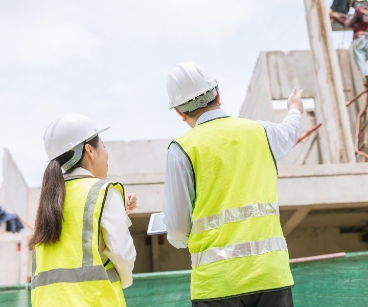 Engineers discussing construction site progress while reviewing plans outdoors.