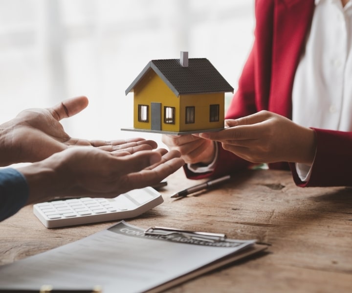 Property sale agreement with house model being handed over.