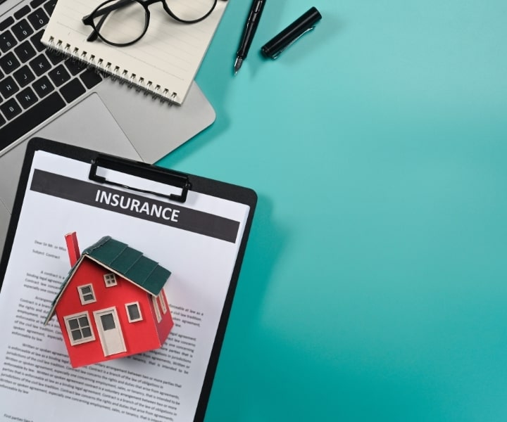 Insurance document with model house, laptop, and office supplies.