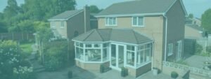 A two-story brick house with a P-shaped conservatory extension, surrounded by a well-maintained garden with lush greenery and a paved patio.
