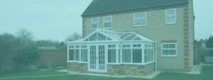 Two-story brick house with green lawn and a large white T-shaped conservatory featuring multiple windows and a glass roof.